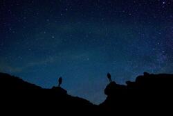 Zwei Menschen stehen vor einem Sternenhimmel.