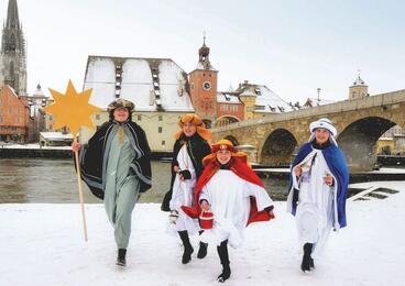 Vier Sternsinger im Hintergrund, der Dom mit der Steinernen Brücke