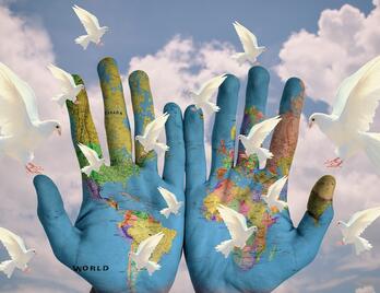 Hände mit Weltkarte und Friedenstauben