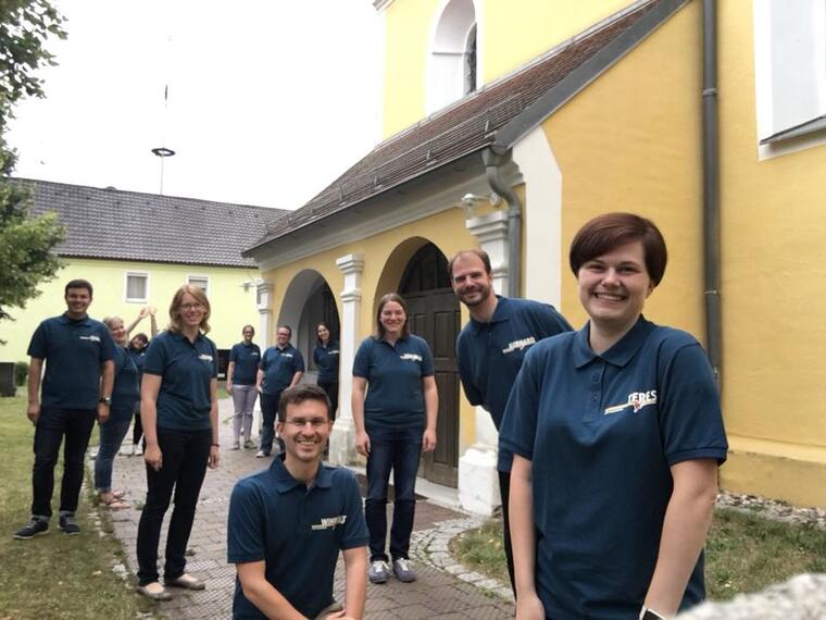 junge Erwachsene im AKM T-Shirt vor der Kirche in Pfatter