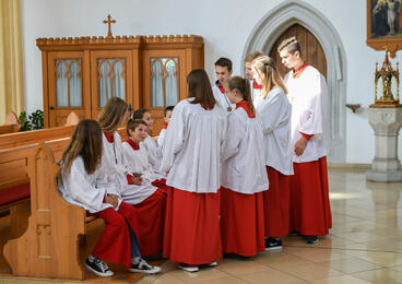 Eine Gruppe Ministranten sitzt und steht in einer Kirche