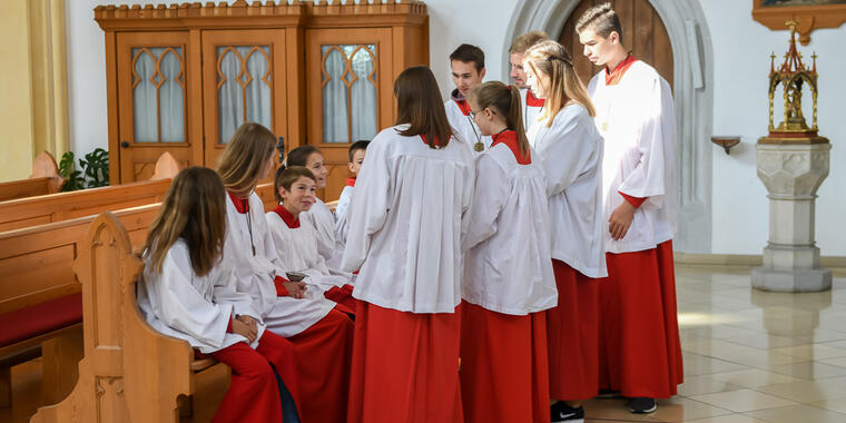 Eine Gruppe Ministranten sitzt und steht in einer Kirche