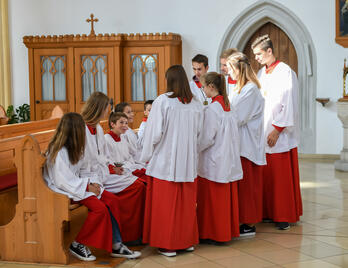 Eine Gruppe Ministranten sitzt und steht in einer Kirche