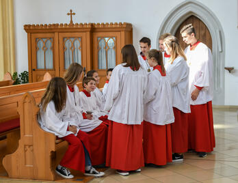 Eine Gruppe Ministranten sitzt und steht in einer Kirche