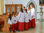 Eine Gruppe Ministranten sitzt und steht in einer Kirche